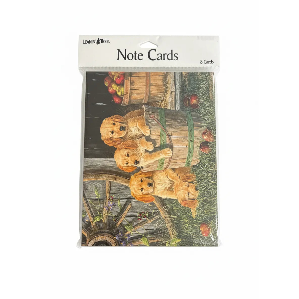 Leanin' Tree Dogs in a Barrel with Apples Note Cards, 8-count stationery set featuring three adorable Golden Retriever puppies in a rustic wooden barrel. This charming outdoor farm scene includes scattered red apples and a vintage wagon wheel. Perfect for dog lovers, these blank greeting cards with envelopes are ideal for thank you notes, birthdays, or everyday correspondence. High-quality animal art stationery for gifting or personal use.