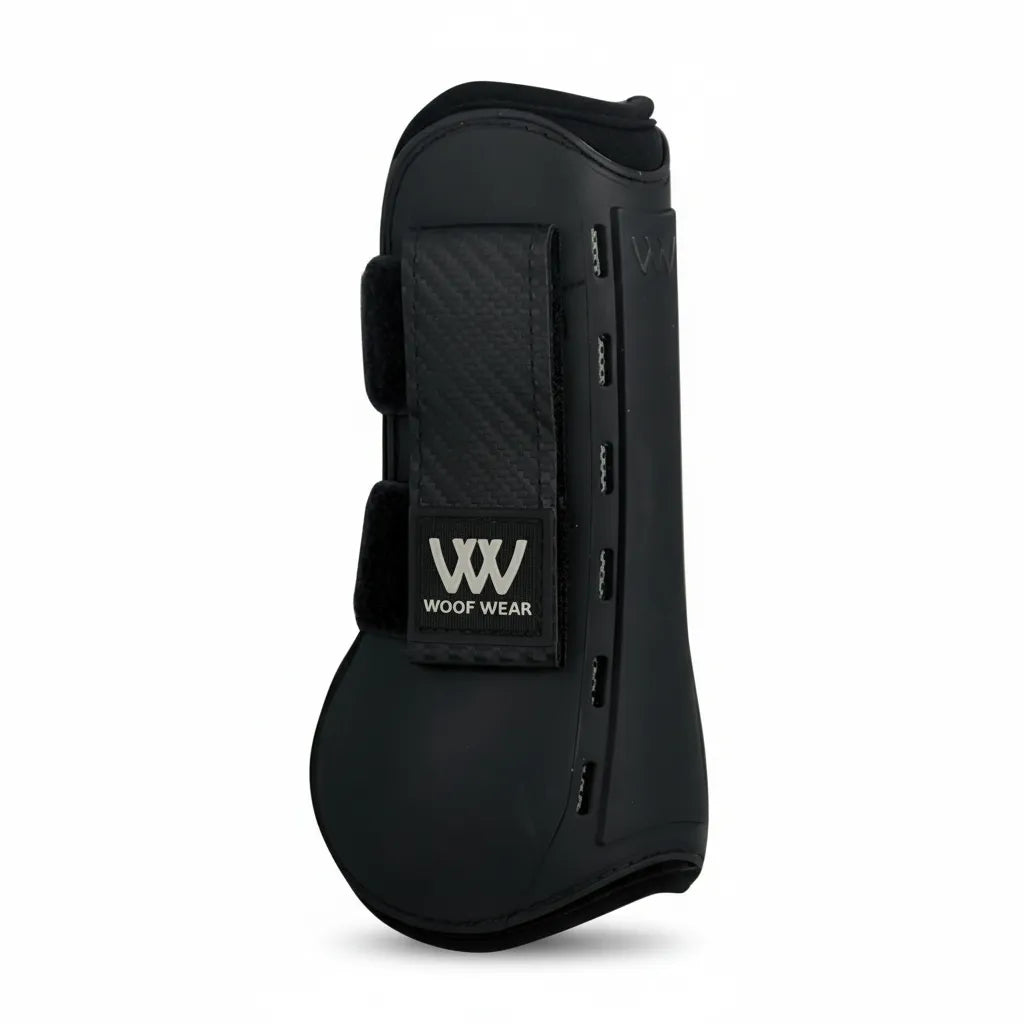 Toklat Pro Tendon Horse Boots by Woof Wear in black. These open-front jumping boots feature a durable hard outer shell and breathable neoprene lining for ultimate impact protection. The sleek design includes secure double-locking velcro straps with a carbon fiber texture and the silver Woof Wear logo. Ideal for show jumping and performance training, these LG/XL boots offer anatomical support and superior leg protection for your horse.