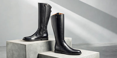 A pair of tall black leather riding boots with a classic equestrian design.