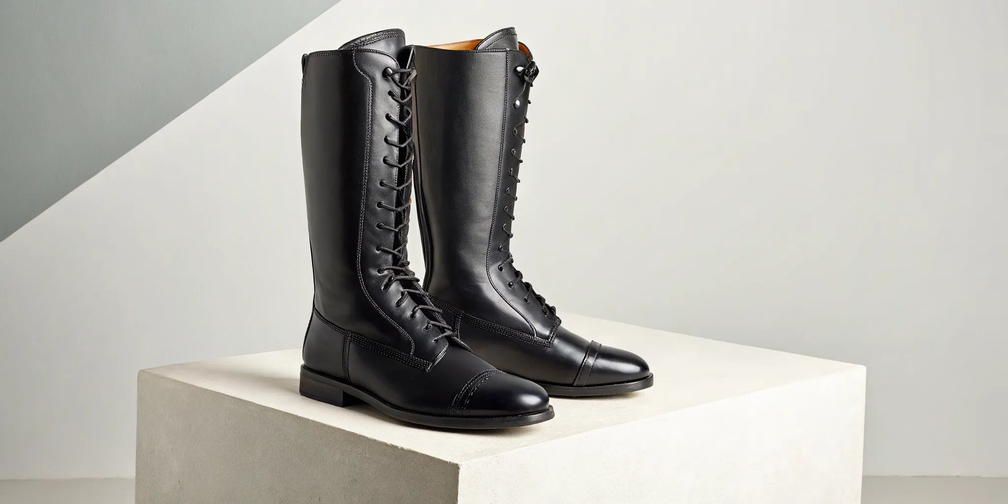 Tall black leather horseback riding boots with laces for English riding.