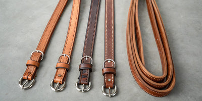 A collection of leather western split reins in different widths and shades.