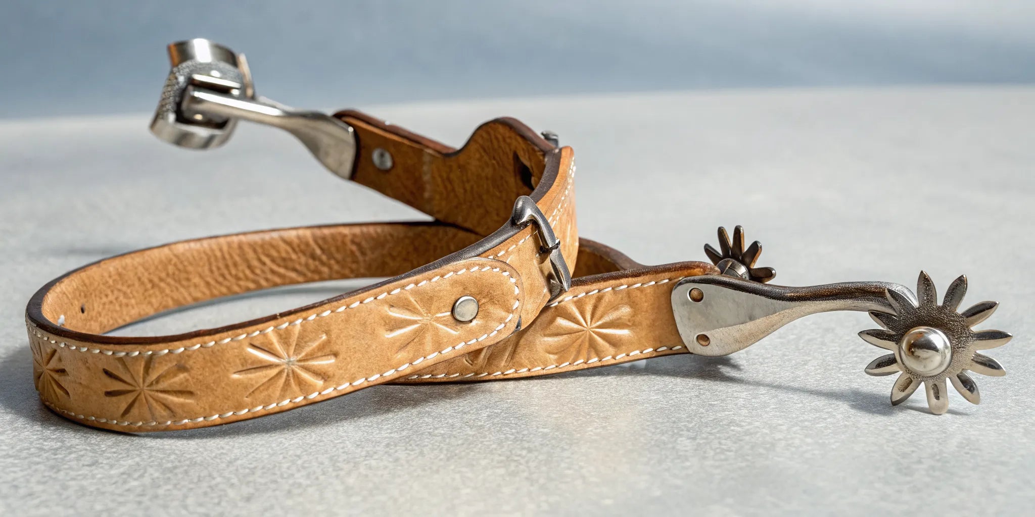 A pair of Western spurs with tooled leather straps and spinning rowels.