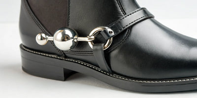 A roller ball spur for horses on a rider's black leather boot.