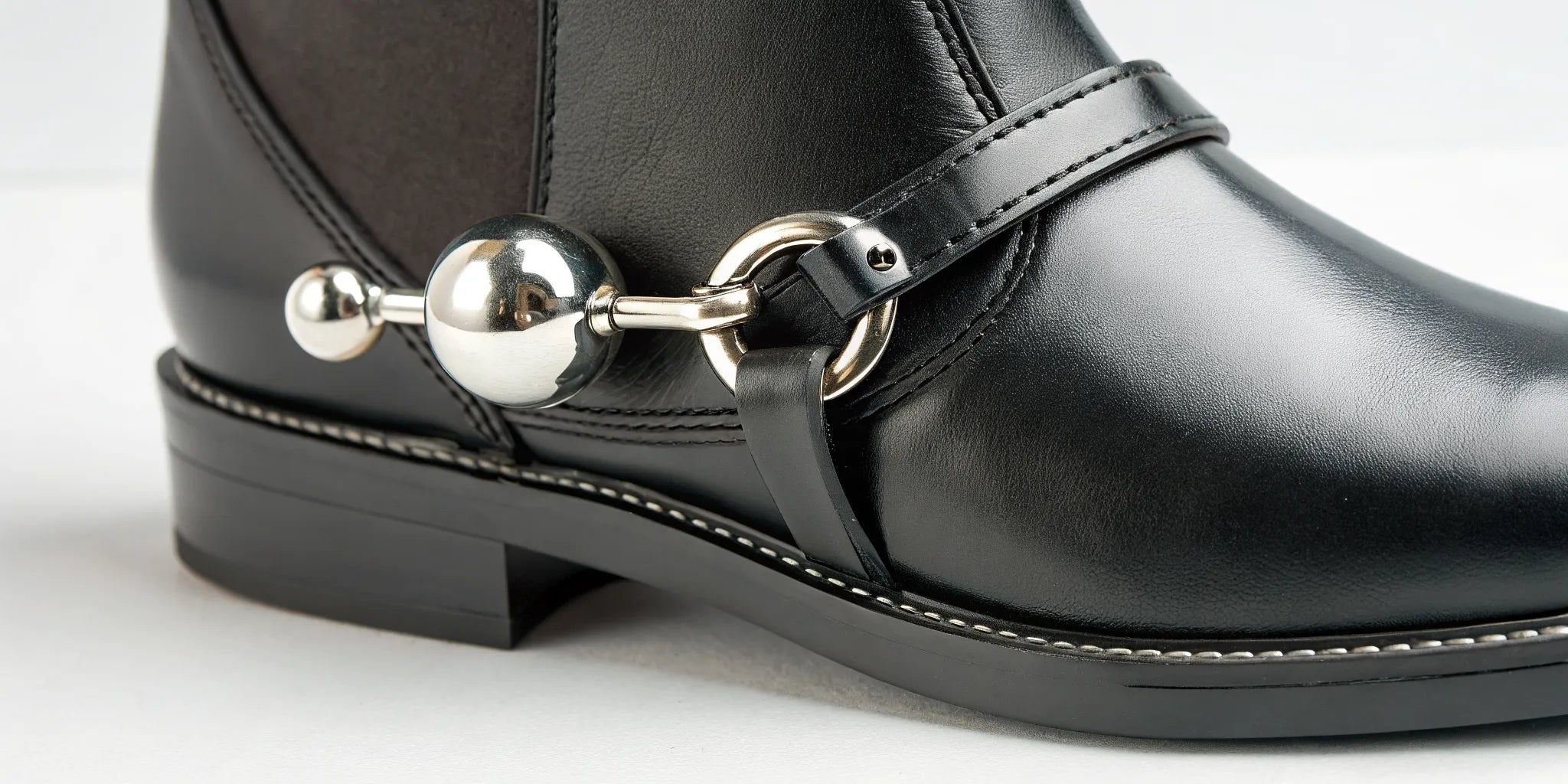 A roller ball spur for horses on a rider's black leather boot.