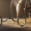 Myler 33 Eggbutt with Hooks 5 1/2" horse bit lying on a sunlit rustic wooden stable floor with hay and a blurred horse in the background.