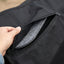 A lifestyle photograph capturing the Toklat MATRIX SHIM Saddle Pad in a rustic ranch setting. The black pad is under a western saddle on a roan horse. A person's hand is visible, lifting the Velcro closure to access the shim pocket, showcasing the pad's practical use.

### 3. Close-Up Detail Shot