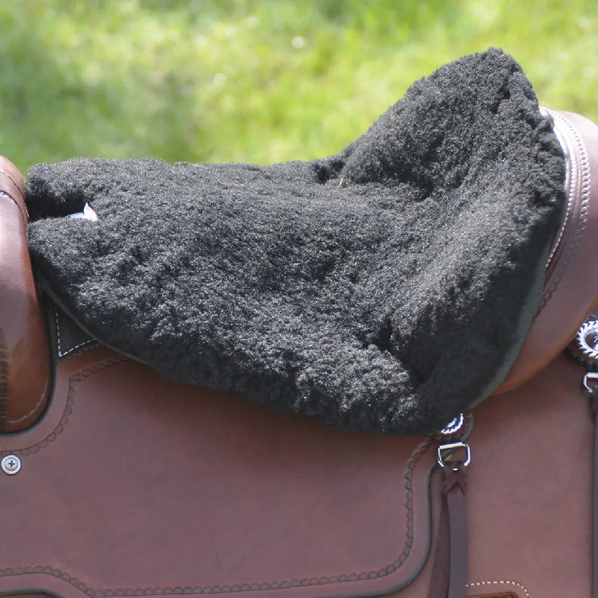 Cashel Fleece Tush Cushion in black, pictured on a brown leather Western saddle. This thick, plush fleece saddle seat pad provides extra cushioning and support for rider comfort during long trail rides. Designed to fit securely over the saddle seat, the high-quality fleece material is breathable and soft, making it an essential equestrian accessory for Western riders seeking a more comfortable horseback riding experience.