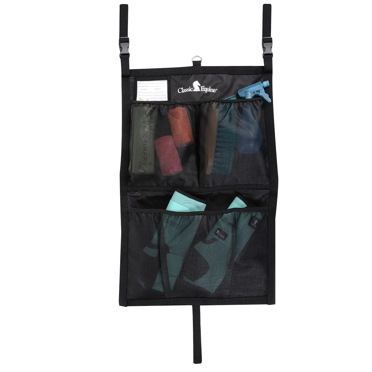 Classic Equine Black Stall Front Bag for horse show organization. This durable black hanging stall organizer features multiple mesh pockets, heavy-duty straps with buckles, and a clear ID window. Shown holding essential horse grooming supplies like leg wraps, spray bottles, and brushes. Ideal for keeping your horse stall tidy and gear easily accessible at home or during competition.