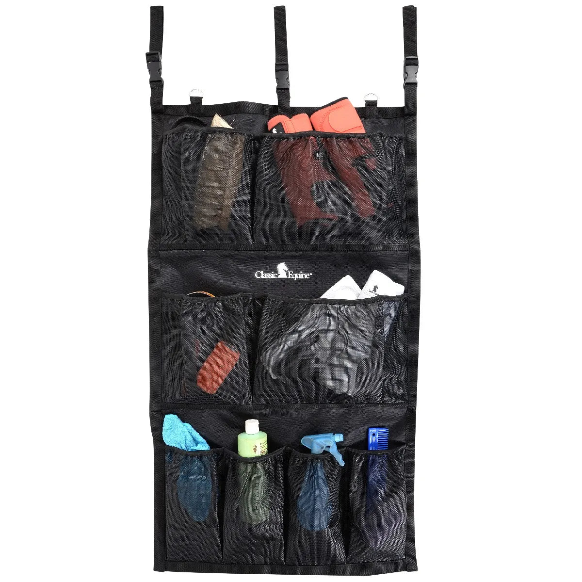 Classic Equine Hanging Groom Case in black, featuring three tiers of mesh pockets for organized barn storage. The top row holds horse brushes and protective boots, while the bottom rows store spray bottles, a grooming comb, and cloths. This durable equestrian organizer includes adjustable hanging straps with buckles and D-rings for easy mounting in stables or trailers. Ideal for keeping horse grooming essentials tidy and accessible.