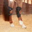Classic Equine MagNTX Hock Wraps in black mesh shown on a chestnut horse's hind legs. These magnetic therapy hock wraps help relieve pain and support joint performance for athletic horses. Featuring a breathable, contoured design with adjustable straps for a secure fit, they are ideal for injury recovery and reducing inflammation. Enhance your horse's mobility with these essential equine leg supports, perfect for use in the stall or during travel.