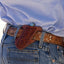 Martin Saddlery Floral Angled Knife Scabbard crafted from rich brown, hand-tooled leather with intricate floral designs. This USA-made leather holster is shown worn at a canted angle on a matching floral western belt, securely holding a pocket knife. Perfect for ranch work and everyday carry, this high-quality sheath adds functional western style to any cowboy outfit.