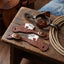 Martin Saddlery Tombstone spur straps with Four Aces card suit tooling on a tack room bench