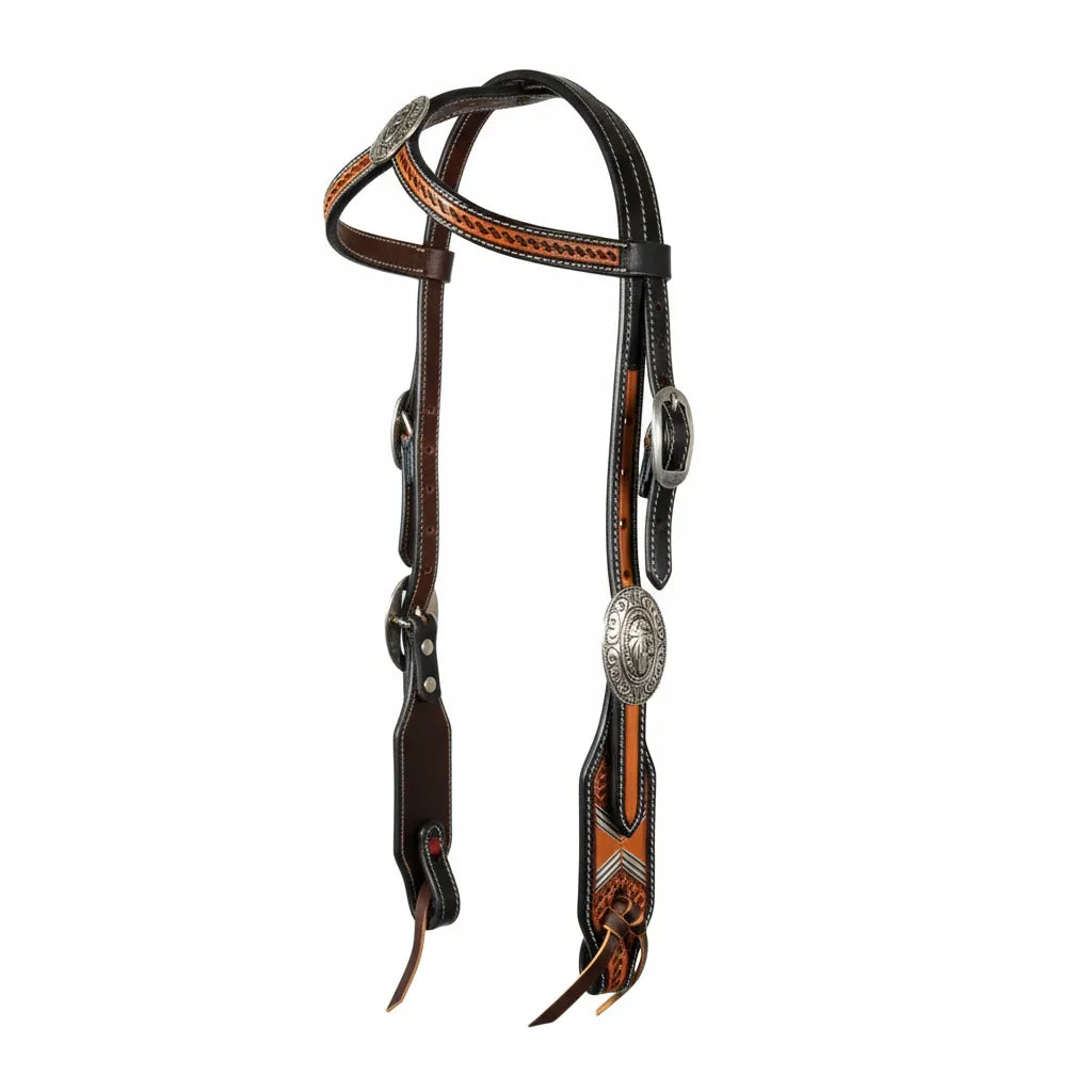 Professional's Choice Tomahawk Headstall featuring basket tooled leather in a striking two-tone design. This western horse headstall showcases dark leather paired with natural tan accents, decorated with intricate silver-toned engraved conchos and adjustable buckles. Durable white stitching and traditional leather ties add a classic touch. A premium piece of western tack perfect for horse shows or trail riding, blending traditional style with Professional's Choice quality.