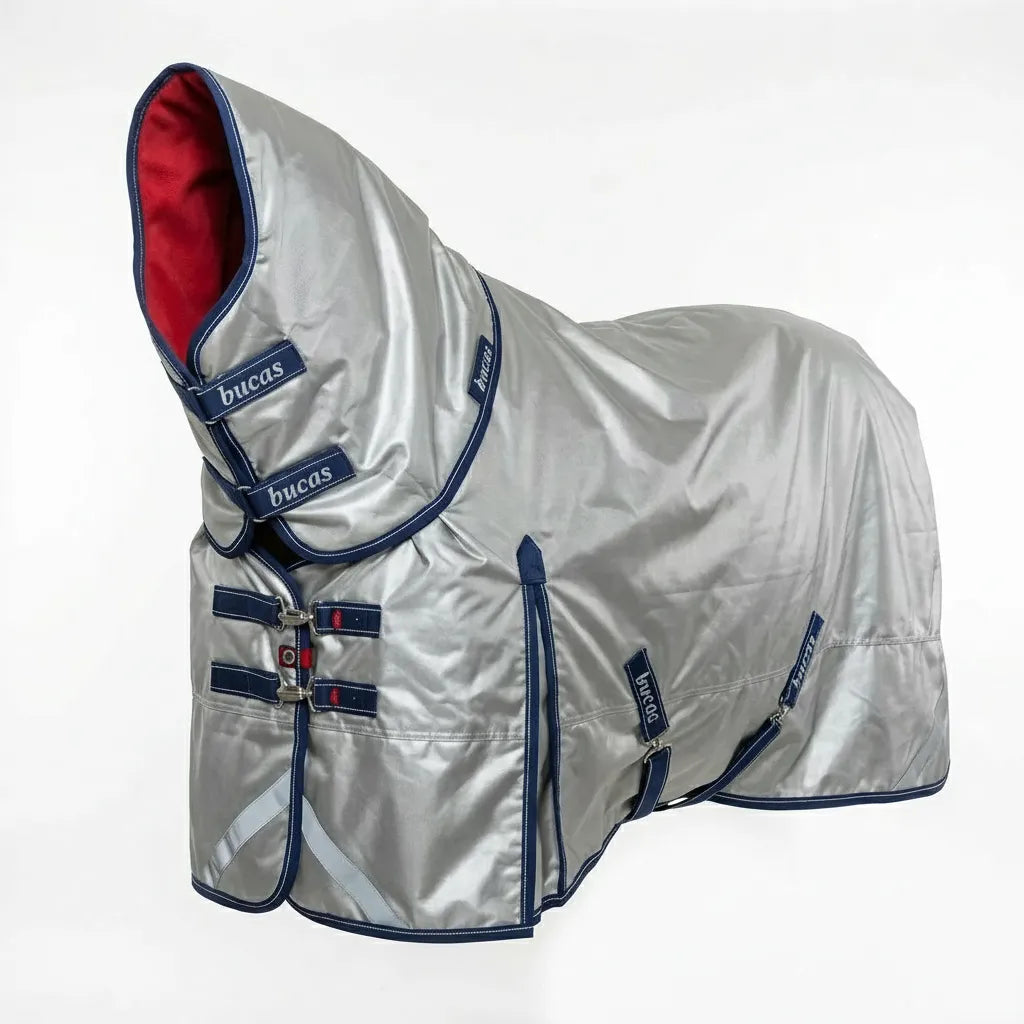 Bucas Power Turnout Light Big Neck Horse Blanket in silver with navy trim and a vibrant red lining. This heavy-duty turnout rug is crafted from durable 1680D ballistic nylon and features a sun-reflective outer shell for temperature control. Designed for broader horses, it includes an integrated neck cover, adjustable front chest closures, and surcingles. High-performance, waterproof equestrian gear perfect for providing maximum protection in variable weather.