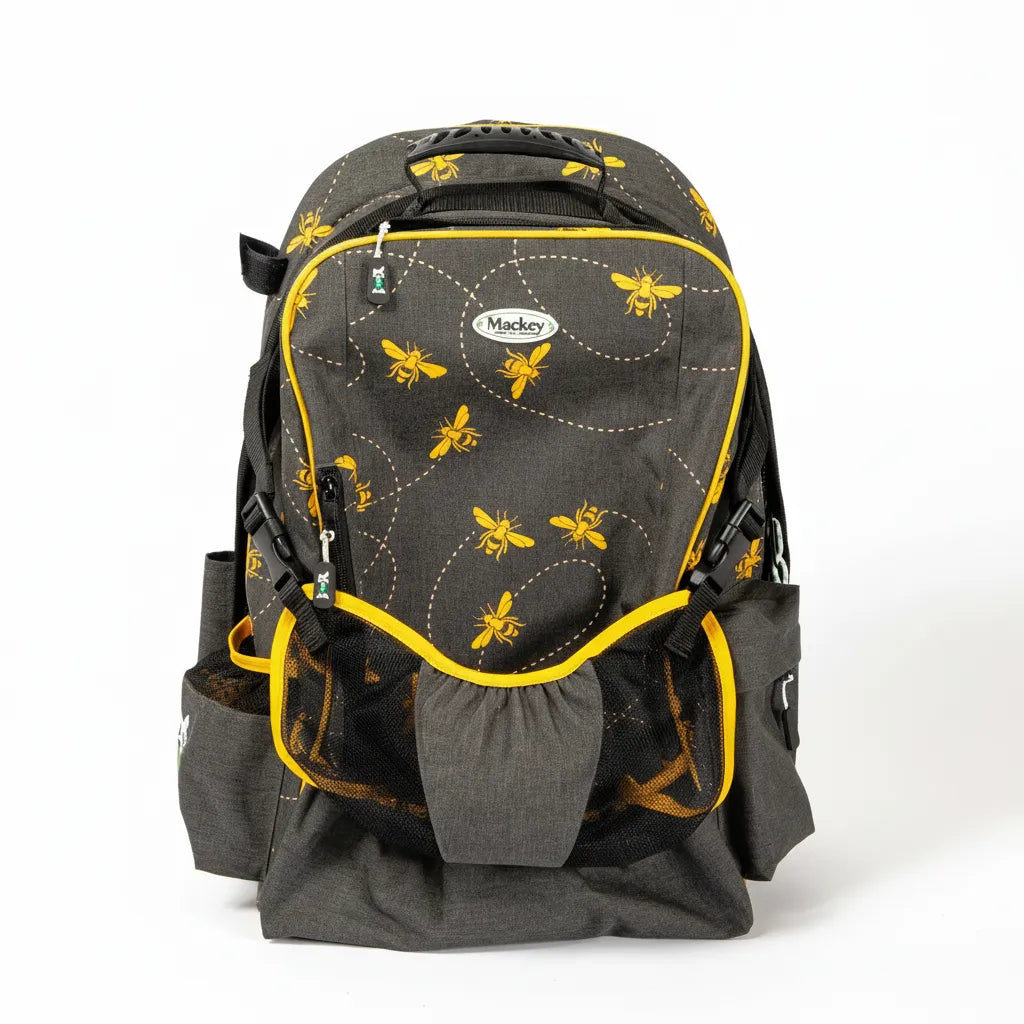 Mackey Bee Mine Equestrian Backpack in charcoal grey with a vibrant yellow bumblebee pattern and trim. This 19" x 13" horse riding gear bag features an integrated mesh helmet sling with buckle closures, side pockets for tall boots, and multiple zippered compartments. A durable and stylish equestrian stable bag with bee flight path embroidery, perfect for organizing riding apparel, helmets, and gear for the barn or horse shows.