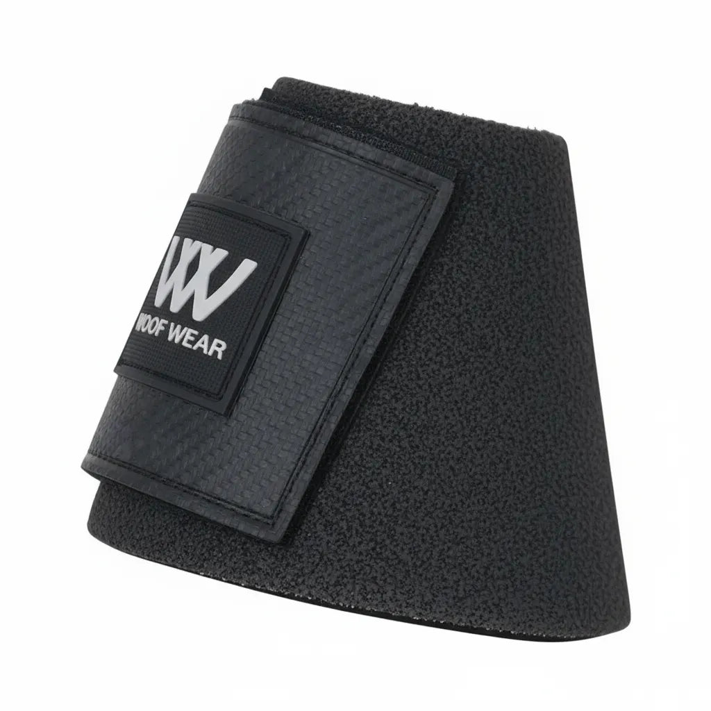 Toklat Woof Wear Kevlar Overreach Bell Boots in sleek black. These high-impact, no-turn boots feature a rugged textured body and a secure carbon-fiber patterned velcro strap with the signature white WW logo. Essential equestrian gear designed for superior hoof and heel protection during high-intensity training, jumping, or turnout.