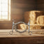 Myler 5 1/2" Weymouth Low Port Barrel horse bit with chain, on a rustic wooden table in a sunlit barn with hay bales.