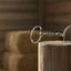 Myler Bridoon stainless steel Comfort Snaffle wide barrel MB 02, 5 inch horse bit on a weathered wooden post inside a sunlit barn, with blurry hay bales and horse tack in the background.