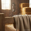 Myler MB 04 loose ring snaffle bit rests on a soft beige blanket draped over a rustic wooden fence post in a barn with hay bales and a sunlit window, ideal for comfort and dressage.