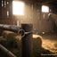 Myler MB 04 Loose Ring Snaffle Bit with copper inlay mouthpiece, hanging on a rustic wooden post inside a sunlit barn with hay bales and a blurred horse in the background.