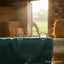 Stainless steel Myler MB 09 Loose Ring Snaffle Bit with copper inlay, resting on a green horse blanket in a sunlit barn with a grazing horse in the background.