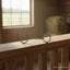 Myler MB 02 Comfort Snaffle sweet iron horse bit with copper inlay, resting on a wooden railing in a sunlit barn.