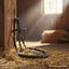 Dark brown leather horse bridle with a Myler MB36 Loose Ring Snaffle bit resting on golden hay in a rustic barn.
