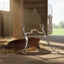 Myler MB 43LP Sweet Iron Low Port Curb Bit with copper inlay, resting on a brown leather headstall and hay on a rustic barn floor with sunlight.