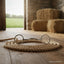 Myler MB 04 loose ring snaffle bit, 6 inch and dressage legal, rests on a coiled rope on a rustic wooden barn floor with hay bales and an open green field in the background.