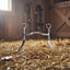 Myler MB 04 Snaffle Bit with sweet iron and copper inlay, standing upright on golden hay in a rustic barn, for horse comfort and control.