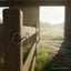 Myler MB 04 Loose Ring Snaffle Bit, 5 inch with copper inlay, hanging on a rustic wooden fence post with a sunlit green pasture in the blurred background.