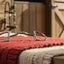 Myler 5 1/2" 33 English Dee with Hooks #89-22337 horse bit resting on a red and beige knitted saddle pad with scattered hay. The background features a rustic wooden stable door opening to green fields.