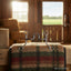 A Myler MB 47 Tom Thumb Snaffle Bit in sweet iron with intricate copper inlay, displayed on a striped horse blanket in a sunlit barn with hay bales and an open view to a green pasture.