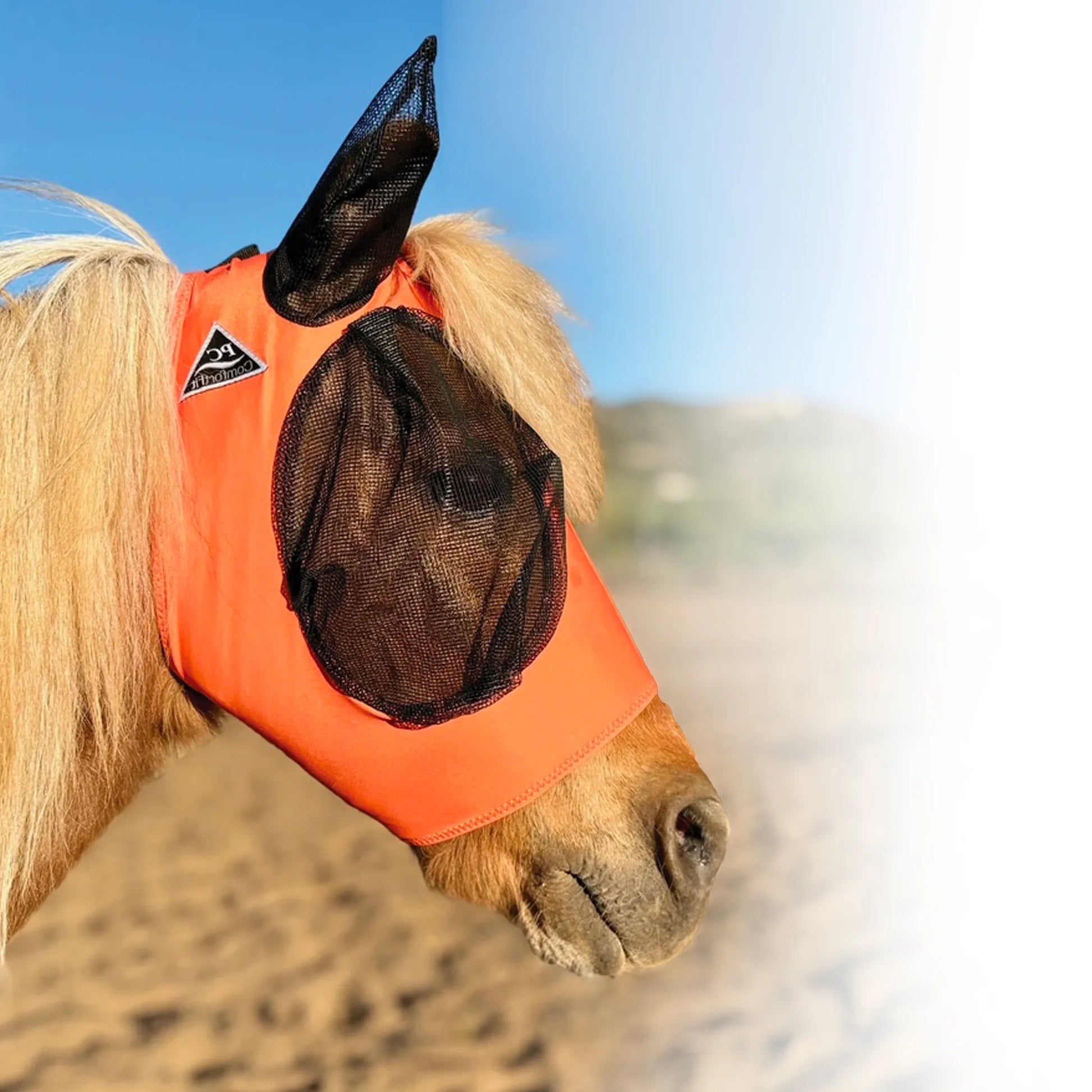 Professional's Choice Comfort-Fit Fly Mask in vibrant orange, featuring breathable black mesh covers for the eyes and ears. This stretchable Lycra horse fly mask provides a smooth, comfortable fit while offering ultimate protection against flies, gnats, and UV rays. A stylish and effective equestrian accessory for summer pest control, perfect for keeping your horse comfortable and protected in the pasture.