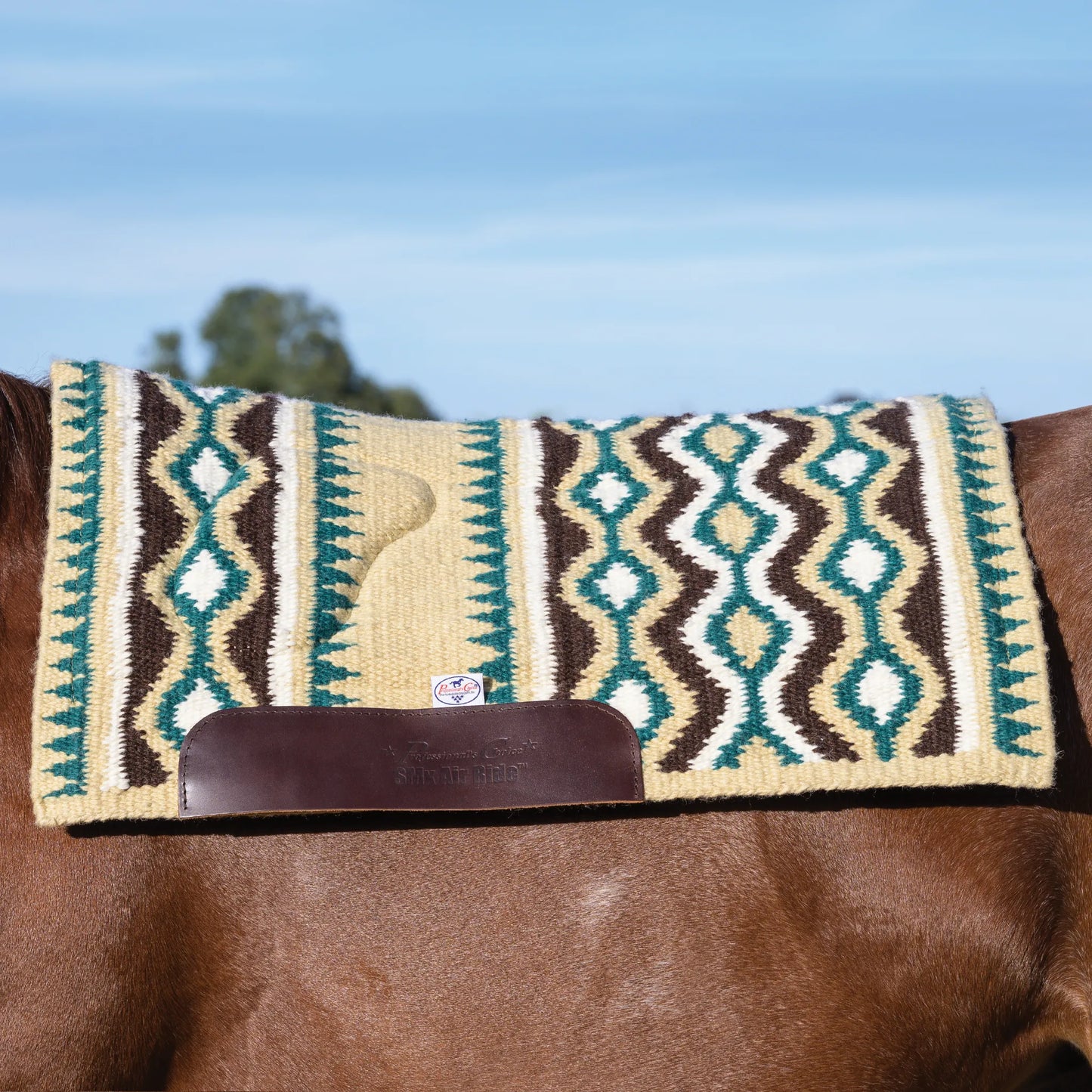 Professional's Choice Comfort-Fit SMX Air Ride Western saddle pad on a chestnut horse. This woven wool pad features a vibrant Southwestern geometric pattern in teal, dark brown, tan, and cream. Includes a contoured spine for a better fit and durable leather wear leathers embossed with the SMX Air Ride logo. High-quality equestrian gear designed for comfort and shock absorption, ideal for Western riding and performance.