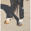 Professional’s Choice Pro Performance support boots in black, providing premium leg protection and impact absorption. These durable equine exercise boots feature multiple secure hook-and-loop straps for a contoured fit. Shown on a horse's hind legs over white socks on a sandy arena surface, they offer essential support for performance horses during training. High-quality equine gear for injury prevention and equestrian performance.