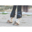 Professional's Choice Pro Performance Horse Boots in black, providing elite support and protection on a horse's hind legs. These breathable, mesh-lined boots feature impact-resistant strike plates and secure quick-fasten straps. Ideal for jumping, dressage, or trail riding, these durable equestrian leg boots offer a comfortable fit over white stockings and hooves on sandy terrain. Essential horse riding equipment for injury prevention and performance.