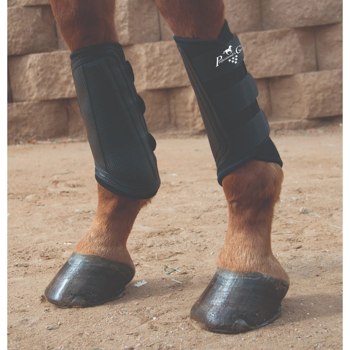 Black Professional's Choice VenTECH Brushing Boots on a chestnut horse's front legs. These breathable horse boots feature a secure three-strap closure and a durable strike pad to protect against interference and impact. Ideal for everyday riding, training, and turnout, these equestrian boots provide lightweight, ventilated leg protection for the cannon and splint bones. High-performance horse gear shown in a sandy arena setting.