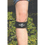 Professional's Choice Knee Compression Strap in black, worn just below the kneecap for targeted patellar tendon support. This adjustable patella strap features a white horse logo and brand name. Ideal for runners knee, jumpers knee, and providing stability during sports and exercise, this compression band offers relief for knee pain and tendonitis. Shown on an athlete’s leg against a lush green leafy background, highlighting its use in active outdoor settings.