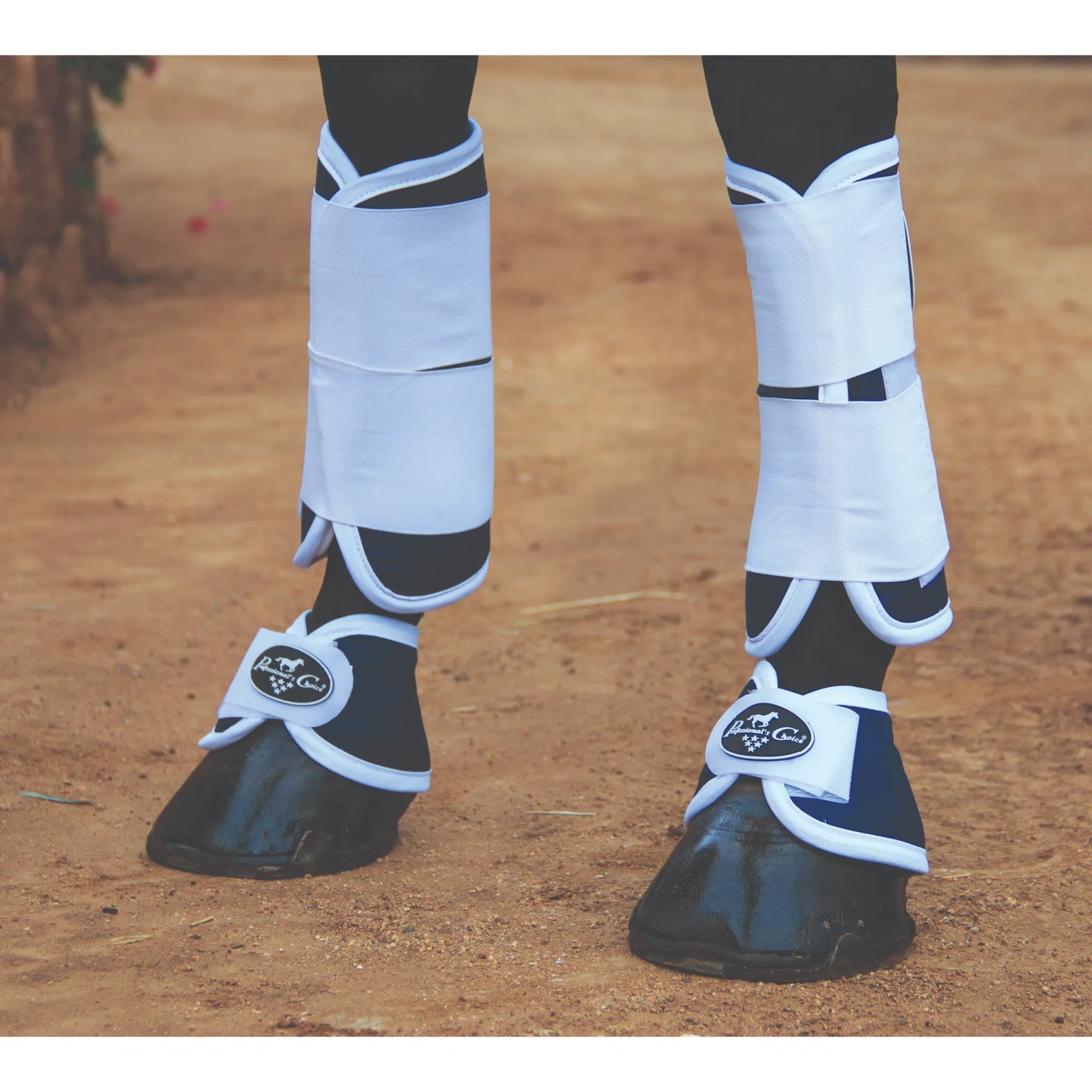 Professional’s Choice Magnetic Bell Boots in navy blue with white trim, designed for horse hoof healing and protection. Shown on a horse's hooves over a dirt surface, these therapeutic bell boots feature magnets to promote blood flow and recovery. Paired with white polo wraps, these boots offer superior overreach protection and equine injury prevention. Perfect for performance horses, hoof care, and therapeutic horse gear.