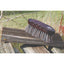 Professionals Choice Wood Series Small Horsehair Brush with a dark mahogany wood handle and ergonomic finger grooves. This professional horse grooming tool features dense, natural horsehair bristles for a high-quality finish. Shown resting on a rustic wooden plank outdoors, this durable and stylish brush is an essential addition to any equestrian grooming kit. Perfect for horse care enthusiasts looking for quality and elegance.