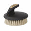 Weaver Leather Palm Brush featuring a contoured black ergonomic handle with a gold logo and soft, dense cream bristles. This professional equine grooming tool is designed for sensitive skin, providing a gentle touch for horse face and body care. The compact, palm-held design ensures maximum control and comfort during stable grooming sessions, making it an essential addition to any equestrian tack box.