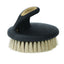 Ergonomic Weaver Leather Palm Brush with soft, cream-colored bristles. This horse grooming brush features a contoured black handle with a gold Weaver Leather logo inlay and a comfortable grip designed to fit perfectly in the palm. Ideal for grooming sensitive areas, finishing touches, and daily livestock care, providing maximum control and comfort for equine maintenance.