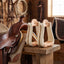 Pair of Weaver Leather 3 inch rawhide covered roper stirrups in a tack room